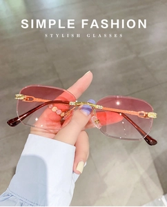 Detail of pink gradient lenses with rhinestone accents on gold metal frameless sunglasses