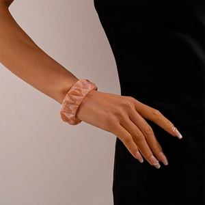 Close-up of thick geometric acrylic bangle with pink marble texture on model wrist
