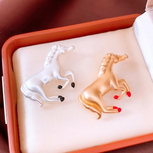 Detailed close-up of gold and silver horse brooches in a premium orange jewelry gift box