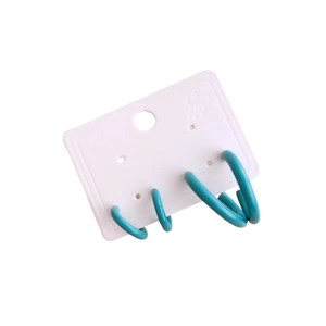 Hollow geometric hoop earrings in teal glossy finish displayed on a white card