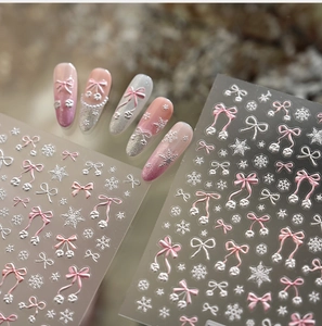 Detailed macro view of 5D embossed nail stickers with pink bows and silver snowflakes