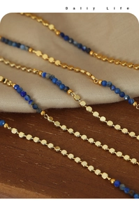 Close-up of titanium steel necklace with gold beads and blue faceted natural stones