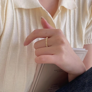 Detailed view of minimalist gold beaded ring worn against a cozy knit sleeve background