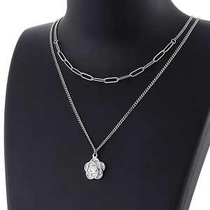 Close-up of silver double-layered necklace with a hollow flower pendant on black bust