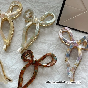 Elegant acetic acid bow hair claws in marble and amber patterns on artistic paper