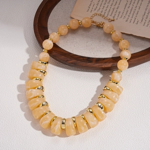 Detail of yellow acrylic beads and golden metal spacers on a vintage style necklace