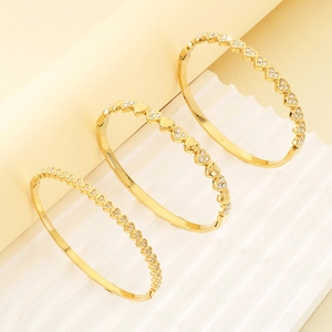 Detailed close-up of three gold-plated heart link bracelets with inlaid diamonds on display