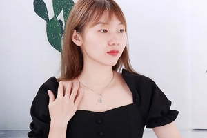 Detailed view of a silver round coin pendant necklace worn on a female model