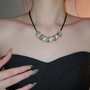 Detail of twisted silver circular metal rings on a black leather cord necklace set