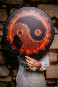 Artistic close-up of shamanic mosaic drum with fire tai chi pattern on stone wall background
