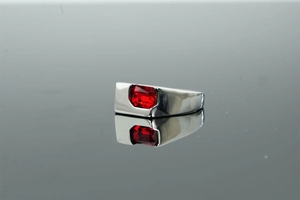 Macro shot of silver ring featuring a rectangular red zircon inlay on polished metal band