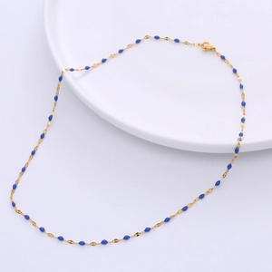 Detailed macro view of 18k gold plated chain with blue enamel lip-shaped charms on ceramic