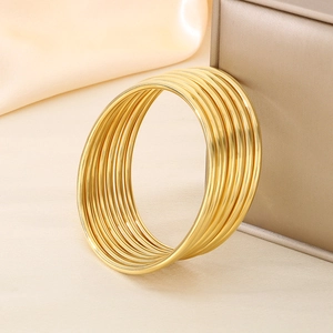Close-up of 18K gold plated multi-layer bangles on a silk background with jewelry box