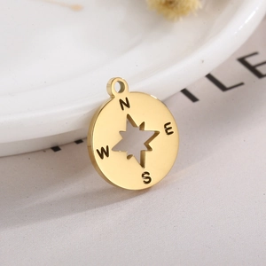 Golden compass star pendant featuring N E S W engraving on a textured surface
