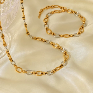 Detail of two-tone gold and silver circular link necklace on luxury champagne silk