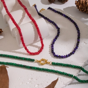 Detailed shot of three colorful beaded necklaces in red, purple, and green on stone stand