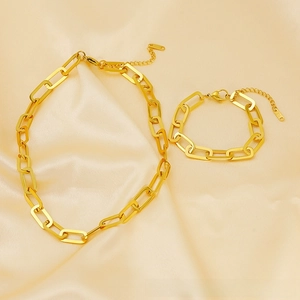 Detail of 18K gold-plated paperclip chain necklace and bracelet set on silk background