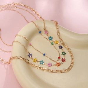 Macro detail of multi-layer gold chain necklace with colorful enamel star pendants