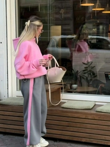 Dettaglio della felpa con cappuccio rosa e pantaloni della tuta grigi con striscia