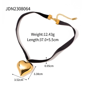 Close-up of a large golden 3D heart pendant on a black velvet choker with size dimensions