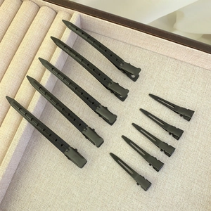 Set of 10 matte black hair clips in two sizes on a beige fabric display tray
