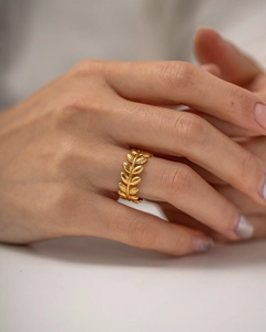 Detailed view of gold olive branch open ring on finger showing leaf texture and metallic finish
