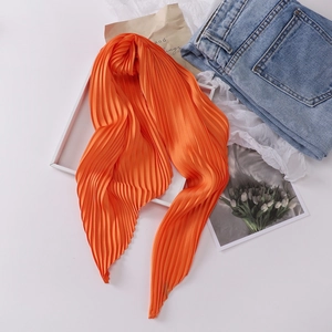 Detailed texture of orange pleated silk scarf for women styled with casual accessories