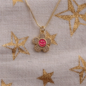 Detail of pink enamel smiley face flower pendant with clear zircons on gold chain