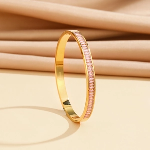 Close-up of pink baguette zircon stones and S. Steel engraving on a gold bracelet