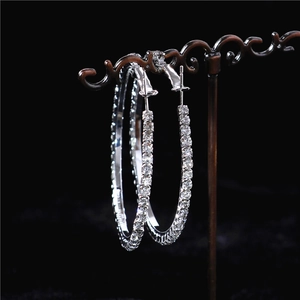 Macro view of oversized silver hoops with embedded sparkling crystals on a display stand