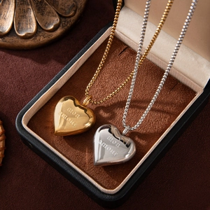 Close-up of gold and silver heart necklaces with Mon Amour engraving in a jewelry box