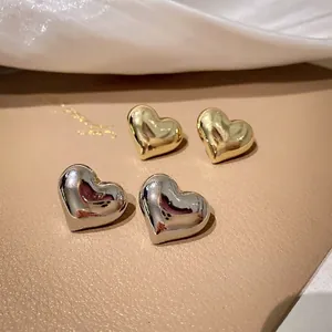 Minimalist polished metal heart stud earrings in gold and silver finishes for women