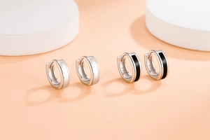 Close-up of minimalist S925 silver hoop earrings with black and white enamel detail