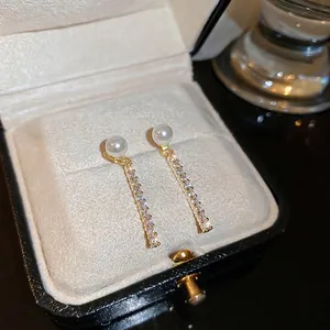 Elegant gold earrings with pearls and pavé cubic zirconia on a velvet display