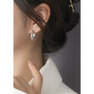 Close-up of model wearing a twisted silver hoop earring with intricate rope texture