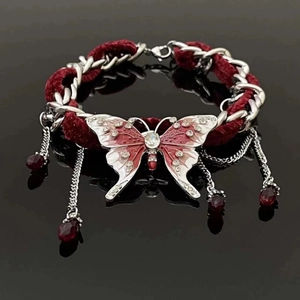 Détail du collier papillon en velours rouge avec chaîne argentée et pompons élégants