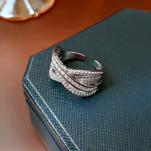 Elegant multi-layer crisscross open ring with zircons on a dark green jewelry box