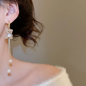 Close-up of brown flocked bear earrings with pearls and gold tassels on a model