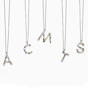 Macro view of five silver S925 necklaces with colorful zircon letter pendants on white