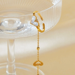 Golden heart ear cuff with mother of pearl and long chain hanging on glass edge