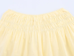 Detail of yellow cotton poplin set showing smocked waist and delicate flower embroidery