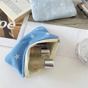 Detailed view of denim star print makeup bag showing internal storage capacity and zipper