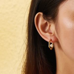 Detailed close-up of 18k gold-plated bamboo hoop earrings with white pearls on a model
