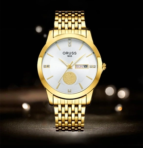 Detail of white watch dial featuring a golden sailboat relief and calendar window