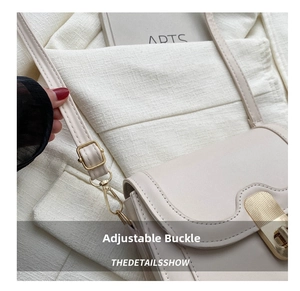 Detail view of cream leather handbag showing gold metal strap buckle and swivel hook hardware