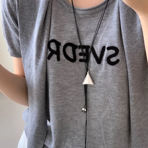 Close-up of minimalist silver triangle pendant on adjustable black leather cord necklace