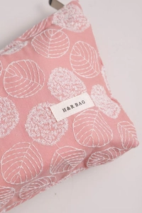 Close-up of pink linen makeup bag featuring leaf embroidery and H&R BAG logo detail
