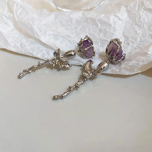 Macro detail of silver rose earrings with purple crystals and intricate leaf textures