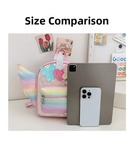 Size comparison of pink unicorn quilted backpack with rainbow wings against a tablet