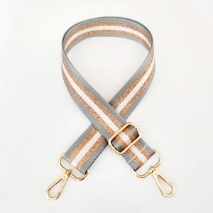 Close-up of adjustable striped nylon bag strap with gold metal hooks and texture